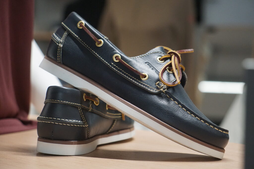 Bootsschuhe aus Leder auf einem Regal, wasserfeste schwarze Schuhe für Ausflüge am Boot