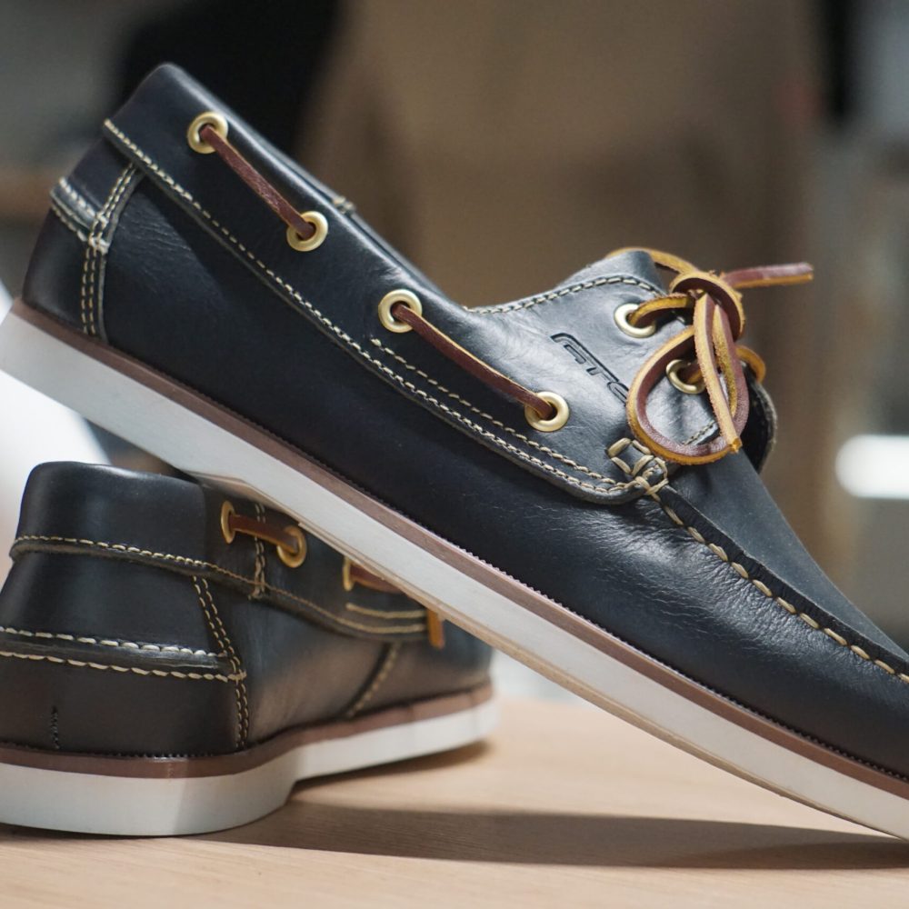Bootsschuhe aus Leder auf einem Regal, wasserfeste schwarze Schuhe für Ausflüge am Boot
